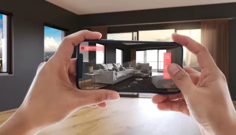 Person using phone AR app to place sofa, table, and decor in a room.